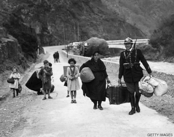 circa 1938: A member of the French frontier troops helps a family of refugees cross the border from Spain during the Spanish Civil War. (Photo by Keystone/Getty Images)