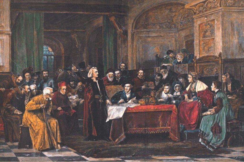 Cristóbal Colón de pie, señalando con la mano, frente a la corte de los Reyes Católicos en un salón decorado; rodeado de nobles, religiosos y consejeros reales. Imagen basada en obra de Wenzel von Brozik.